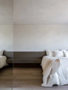 A minimalist bedroom with a wooden bed frame and fabric bedding.
