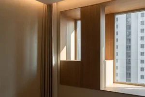 A modern residential space featuring a wooden pane wall and window with a view of an adjacent building.