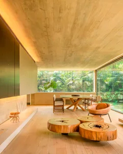Modern living room featuring concrete coffee tables, wood flooring, and a large window overlooking a green landscape.
