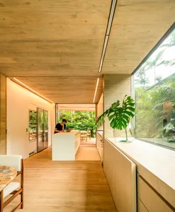 Contemporary residential kitchen featuring minimalist design, concrete finishes, and a large window showcasing lush greenery.