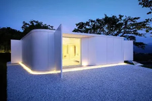 A modern minimalist house with white panels and large glass windows.