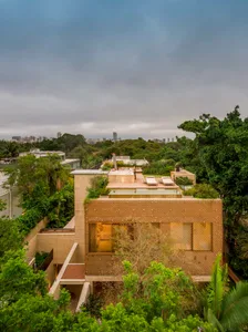 An elevated view of a modern house with a wooden exterior surrounded by lush greenery.
