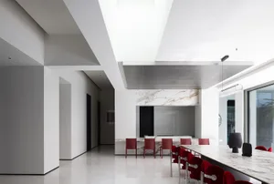 A modern interior design featuring a marble bar counter with red chairs and a white marble floor.