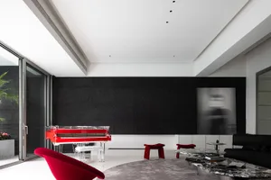 A modern minimalist living room with a red piano, white furniture, and grey rug.