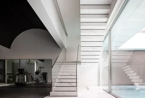 Modern interior featuring a marble staircase adjacent to a glass wall with a gym and pool area.