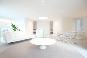 Modern minimalist living room featuring a white sofa, round coffee table, and concrete floor.