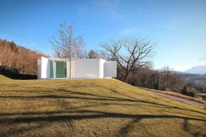 Modern house with white exterior and curved design on a grassy hill