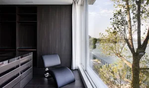 Modern living room featuring a sleek, black leather chair by the window.