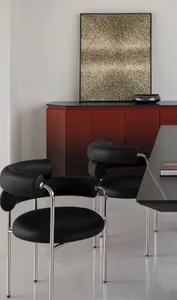 A modern living room featuring black metal chairs and leather upholstery, with a minimalist abstract painting and red furnitu