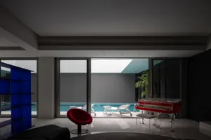 Modern living room featuring a concrete wall, floor-to-ceiling glass windows, and a minimalist interior design.