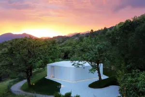 A minimalist residential architecture featuring clean lines and a concrete exterior at sunset.