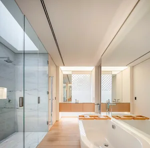 Modern minimalist bathroom with marble walls, wood accents, and a large glass shower.