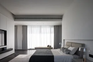 A modern bedroom with minimalist decor, featuring curtains, a bed, and a nightstand.