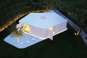 Modern minimalist house with a white concrete exterior, featuring large windows and a minimalist interior design.