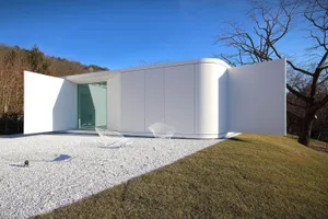 A modern residential exterior featuring glass walls and white paneling.