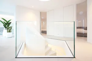 Modern white interior space with a glass staircase and minimalist design