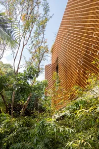 A modern building with a brick exterior surrounded by lush greenery.