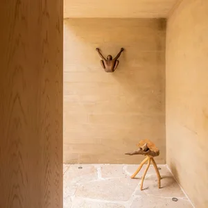 A minimalist interior design featuring a concrete floor and wall, with a sculpture on the wall
