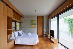 Modern bedroom with concrete accent wall and wooden flooring.