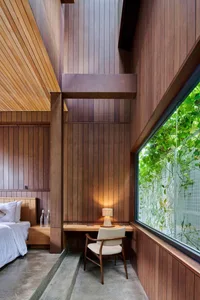 A minimalist bedroom with wooden walls and a desk area.