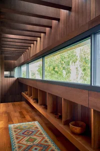 A modern interior with a wooden staircase, featuring a colorful patterned rug and built-in shelves with wooden bowls.