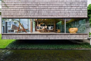 A modern residential interior featuring wood elements and a serene water view.