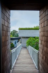 A wooden pathway with concrete railings and a green roof on a rooftop.