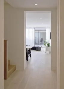 Modern hallway with white wooden flooring, glass doors, and minimal decor.