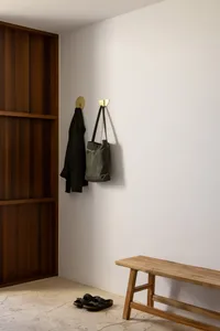 A modern entryway featuring a wooden bench, metal hooks, and a wooden door.