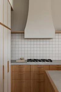 Modern kitchen with white tiled backsplash, wooden cabinetry, and a concrete countertop.