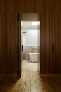 Modern bathroom with a white freestanding bathtub, tiled floor, and a brass faucet.