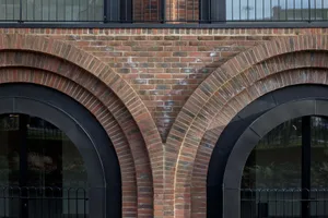 A modern brick wall with an intricate design and black metal railings.