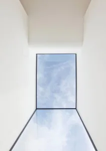極簡室內設計中，玻璃天花板映照著多雲的天空。