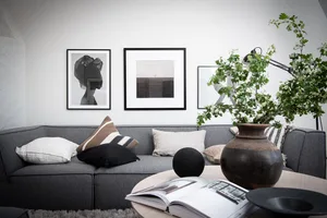 A modern, minimalist living room featuring a comfortable sofa adorned with neutral throw pillows and accentuating a floral ar