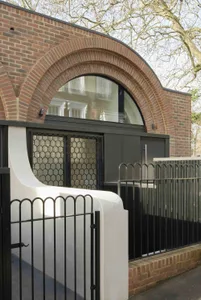 A modern building with an arched brick facade and a black metal fence.