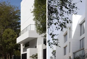 Contemporary residential building with white stone and glass exterior.