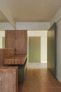 A minimalist bathroom with concrete walls and floor, featuring a rectangular sink with a metallic faucet and a large mirror a