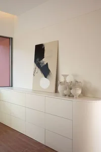 A minimalist interior featuring ceramic vessels on a white cabinet.