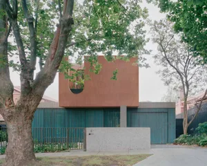 A modern house with metal cladding and greenery on the exterior, surrounded by trees, in an urban setting.