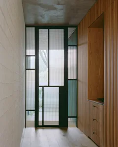 Modern minimalist entryway with glass panels and wooden detailing.