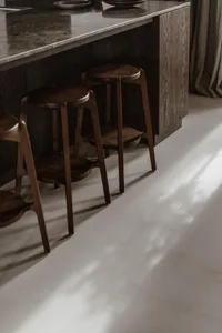 A modern kitchen with dark wooden stools and a polished countertop.