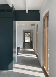 A minimalist hallway with concrete flooring and wooden doors.