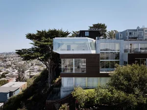 A modern residential building featuring large glass walls and a unique angular design.