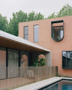 Modern house exterior featuring clay brick, concrete walls and large windows.
