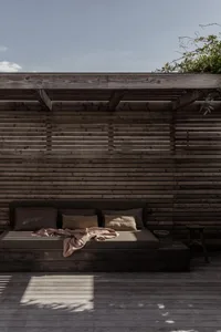 A modern outdoor space featuring a wooden lounger against a wooden wall and floor.