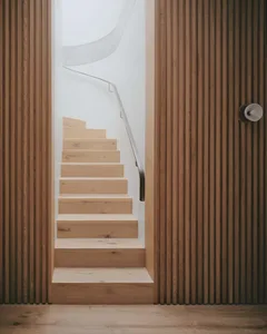 A minimalist staircase with wood steps and a metal railing.