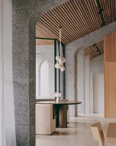 Modern industrial-style lobby with concrete walls and slatted wooden ceiling.