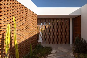 A modern entranceway featuring a brick wall and a wooden lattice gate.