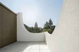 An architecturally minimalist balcony featuring concrete walls and a curved design.