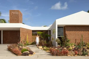 A modern residential exterior featuring brick, concrete, and glass materials.
